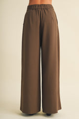 woman wearing brown wide-leg trousers with an elastic waistband and side pockets