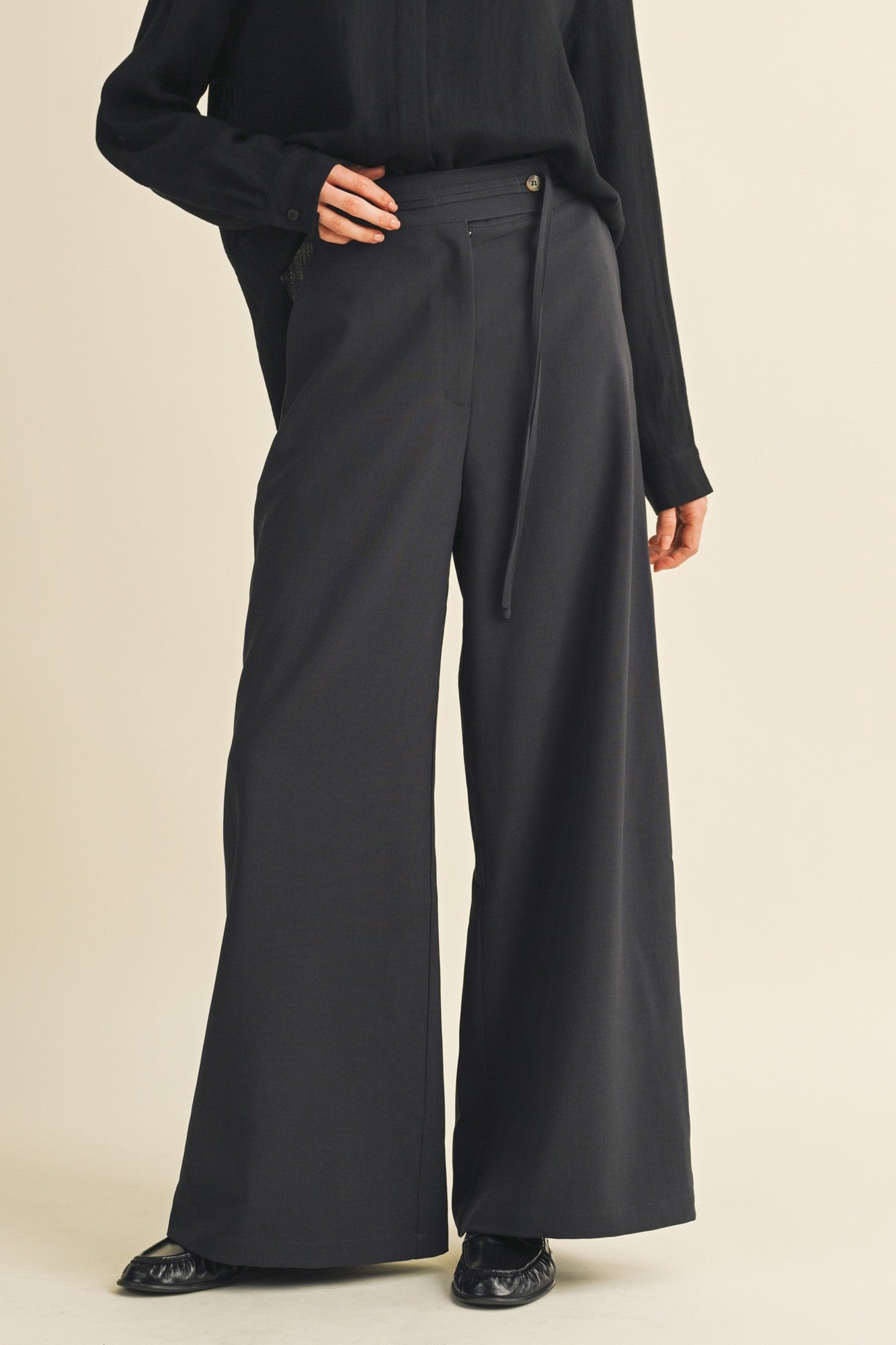 woman wearing black wide-leg trousers with a high waist and tie detail