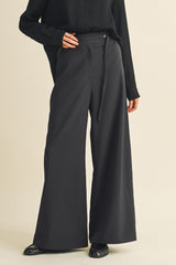 woman wearing black wide-leg trousers with a high waist and tie detail