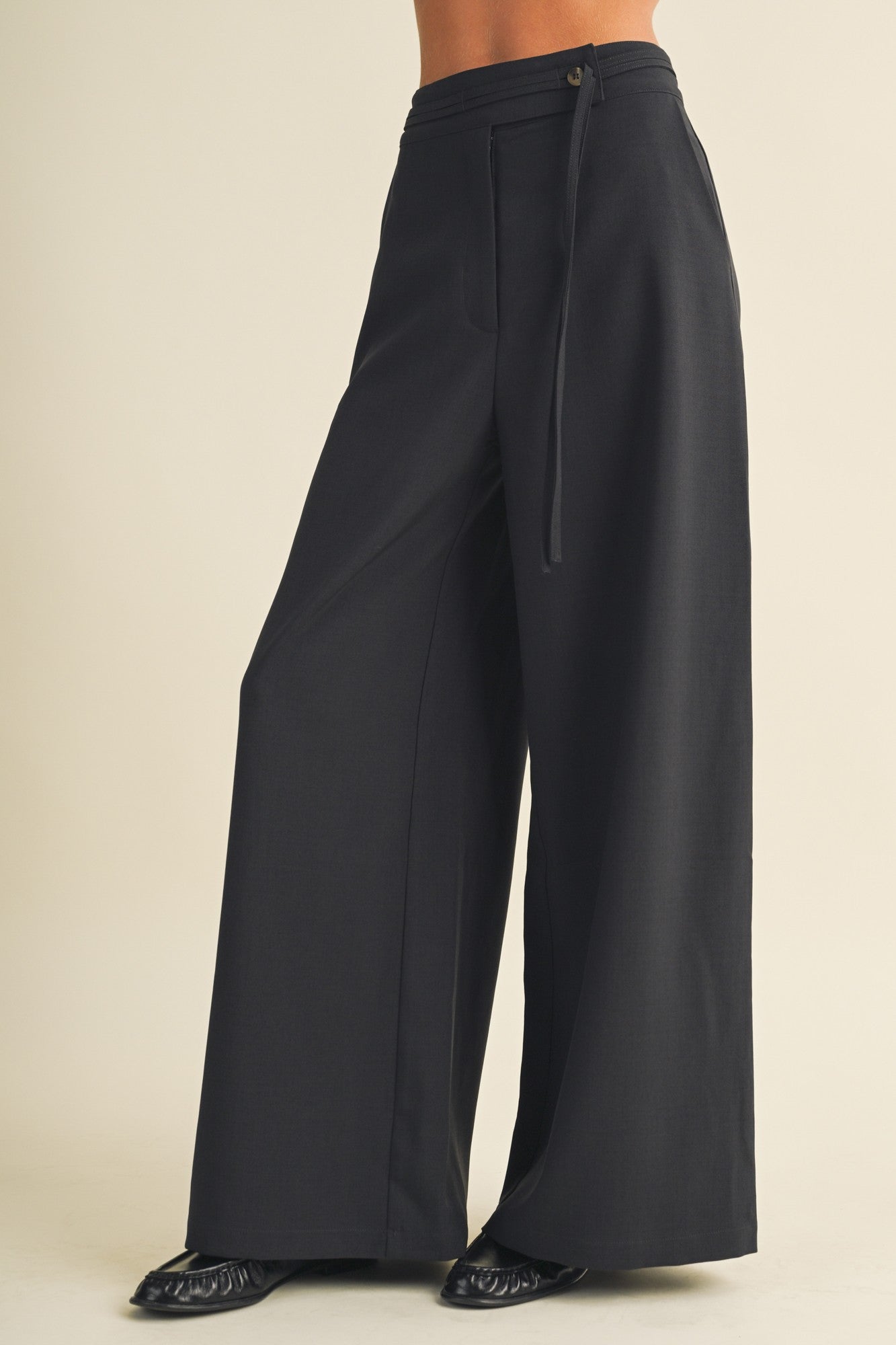 woman wearing black wide-leg trousers with a tie waist and side pockets