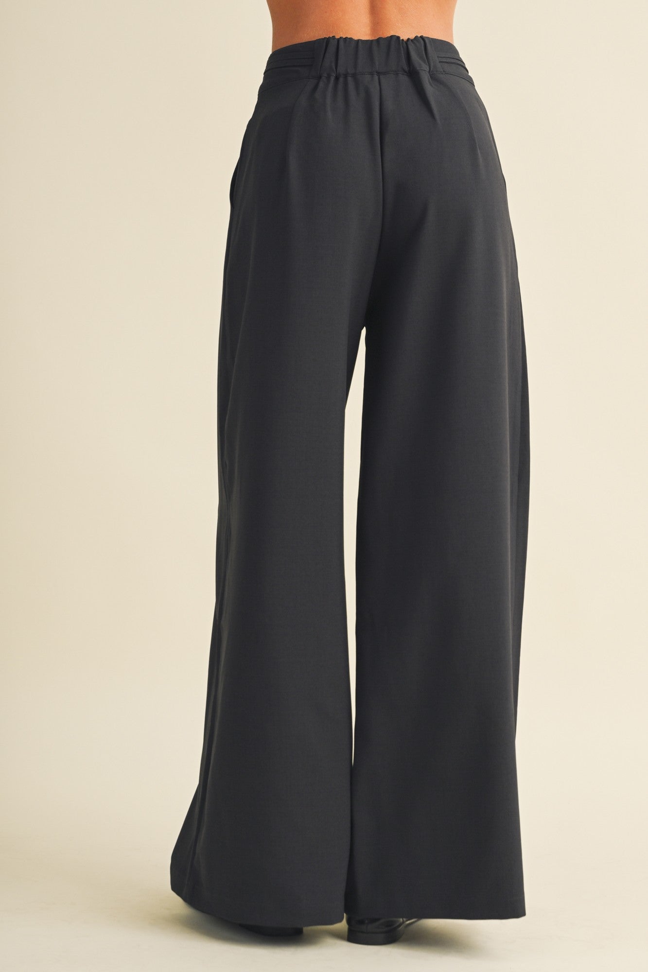 woman wearing black wide-leg pants, back view showing elastic waistband and flowy silhouette