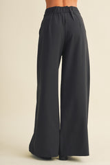 woman wearing black wide-leg pants, back view showing elastic waistband and flowy silhouette
