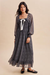 woman wearing a black and white polka dot maxi dress with puff sleeves and a ribbon tie at the neck