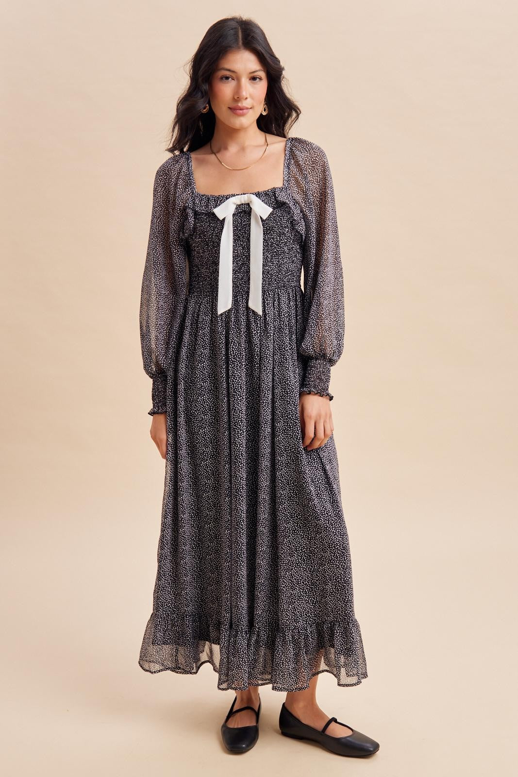 woman wearing a black and white patterned long sleeve maxi dress with a square neckline and ribbon detail