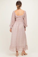 woman wearing a blush floral print maternity dress with long sleeves and a flowy hem, showing a baby bump from the back