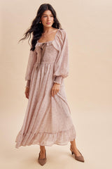 woman wearing a blush long sleeve maxi dress with ruffle details and a bow at the neckline, styled with brown heels