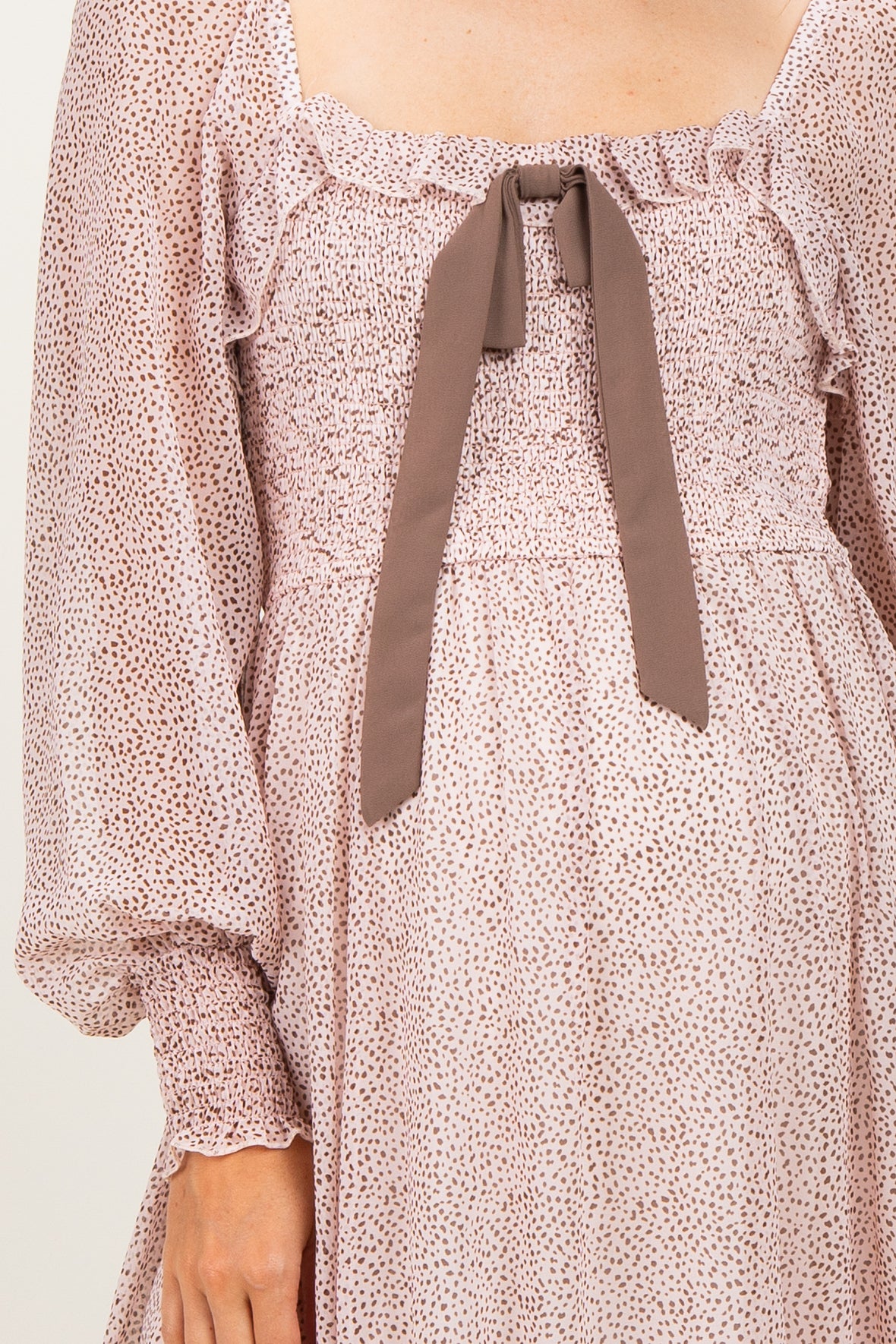 maternity wear in a blush pink dress with a smocked bodice and a bow at the neckline, featuring long puff sleeves
