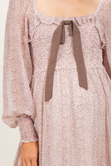 maternity wear in a blush pink dress with a smocked bodice and a bow at the neckline, featuring long puff sleeves