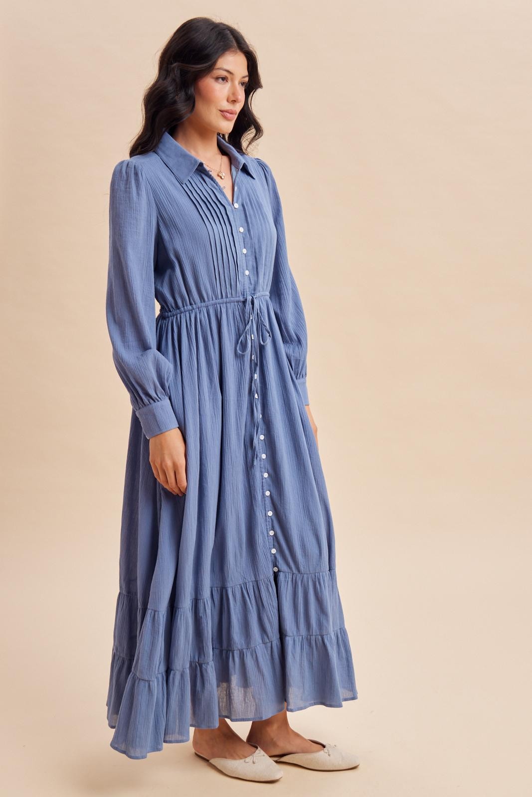 woman wearing a light blue long sleeve maxi dress with a button-down front and tiered ruffle hem