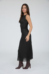 woman wearing a black lace midi dress with a fitted bodice and flowing skirt, paired with brown ankle boots