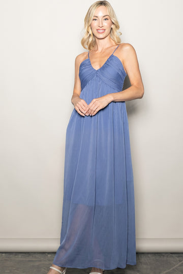 woman wearing a flowy blue maxi dress with a v-neck and spaghetti straps, standing against a neutral background
