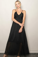 woman wearing a black maxi dress with thin straps and a flowy silhouette