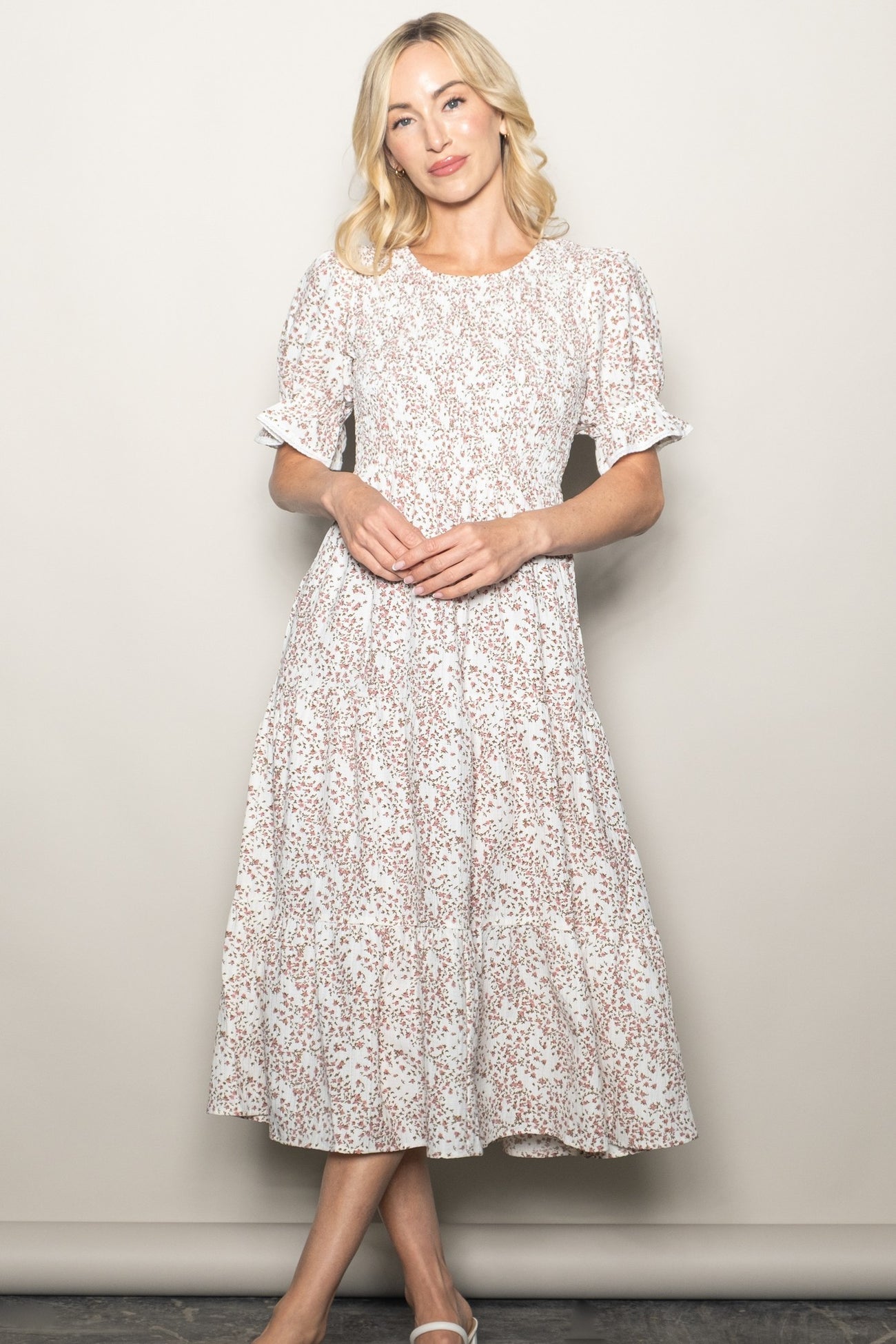 woman wearing a white floral midi dress with puff sleeves and a tiered skirt