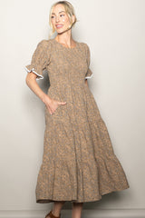 woman wearing a brown floral midi dress with puff sleeves and pockets, standing against a neutral background