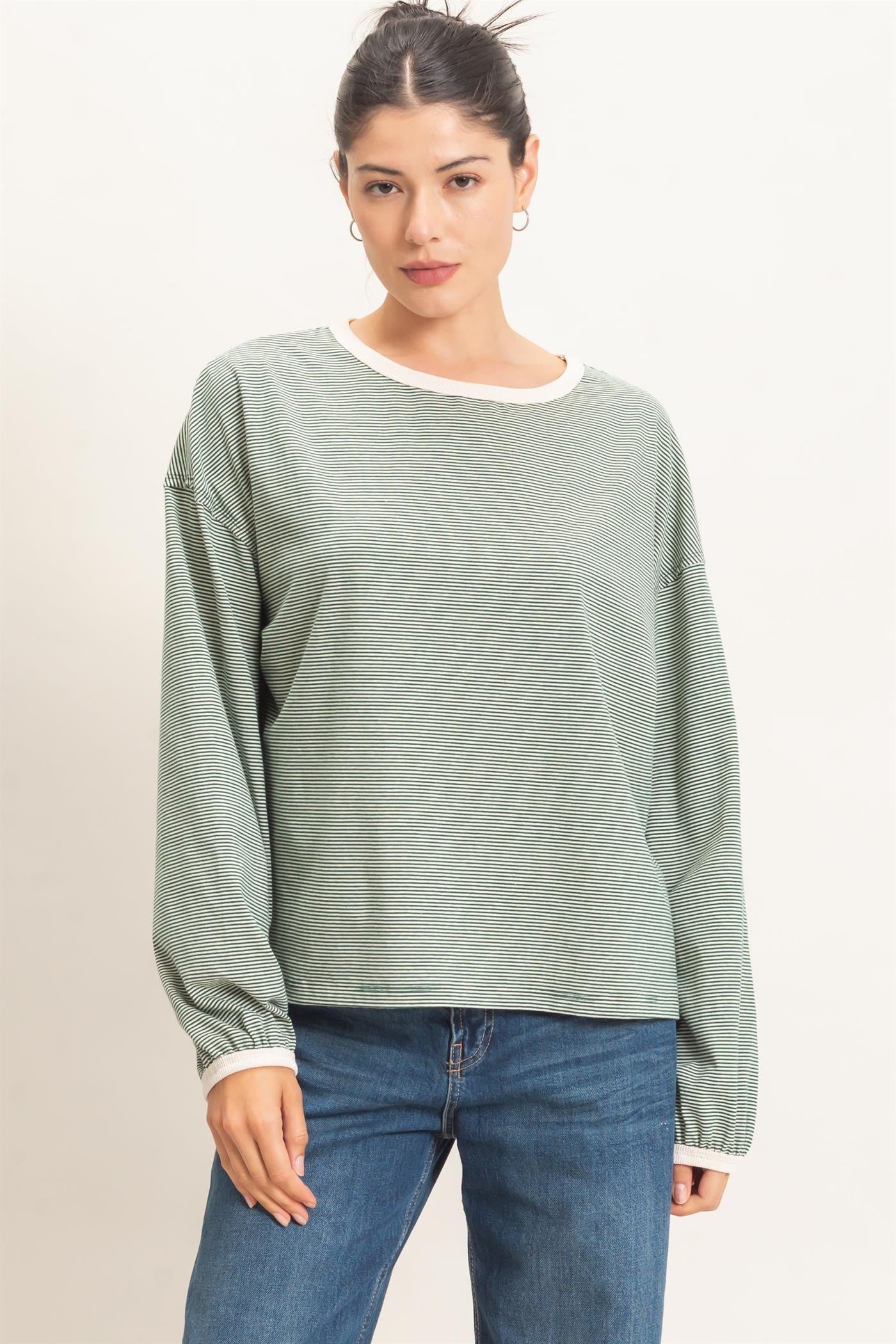 woman wearing a green striped long sleeve top with a white neckline, paired with blue jeans
