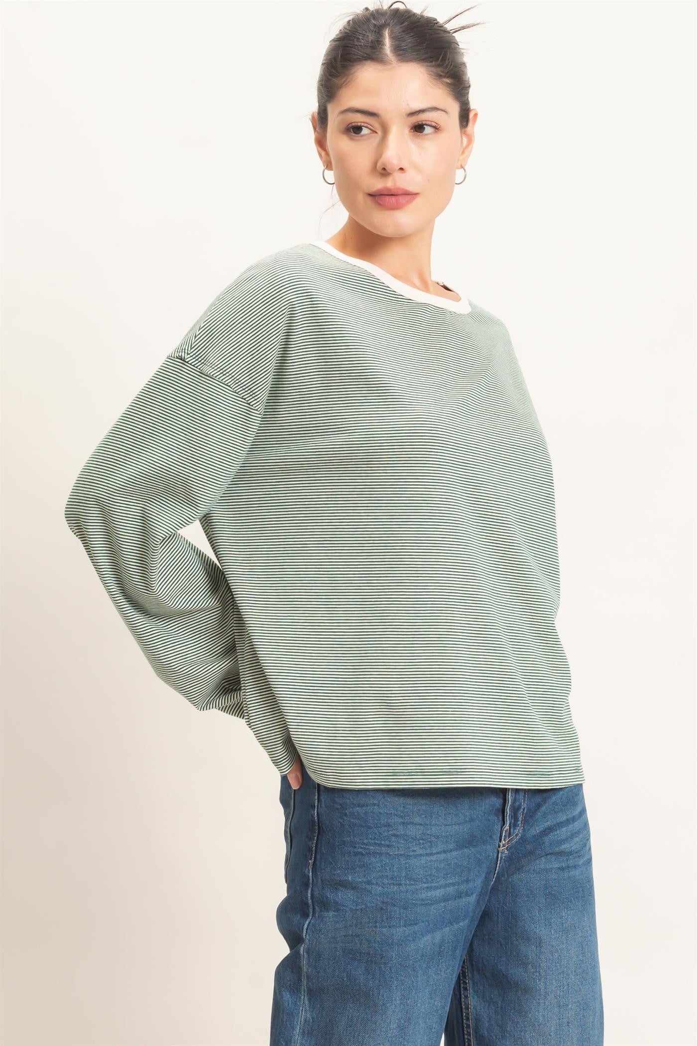 woman wearing a green striped long sleeve top with a white neckline and blue jeans
