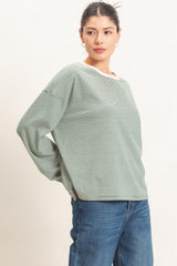 woman wearing a green striped long sleeve top with a white neckline and blue jeans