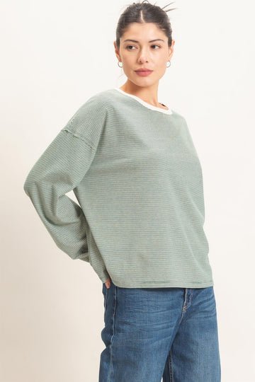 woman wearing a green striped long sleeve top with a white neckline and blue jeans