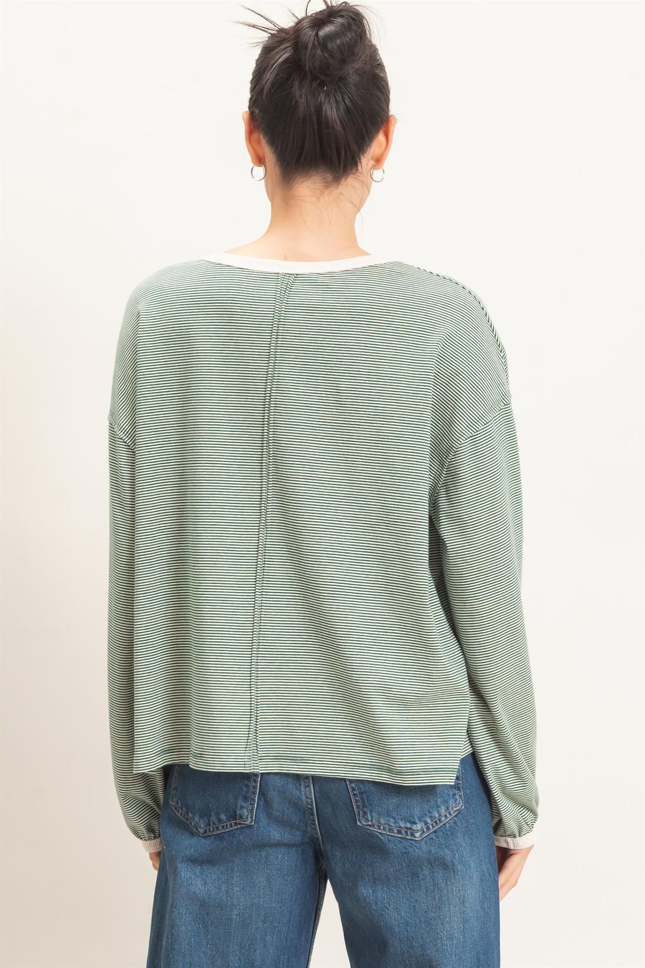 woman wearing a green striped long sleeve top with a relaxed fit and back seam detail, shown from the back