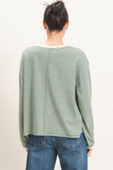 woman wearing a green striped long sleeve top with a relaxed fit and back seam detail, shown from the back
