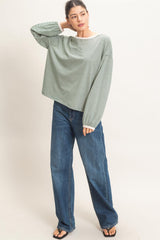 woman wearing a green striped long sleeve oversized top and blue wide-leg jeans