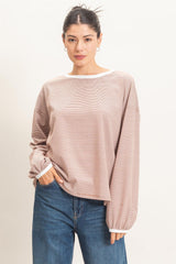 woman wearing a light brown striped long sleeve top with a relaxed fit and ribbed cuffs, paired with blue jeans