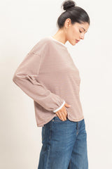 woman wearing a brown and white striped long sleeve top with a relaxed fit and light blue jeans