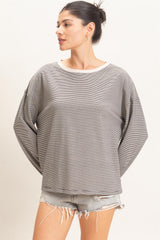 woman wearing a gray and white striped oversized sweatshirt with rolled cuffs and distressed denim shorts