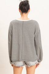 woman wearing a gray striped oversized long sleeve top with a relaxed fit, paired with distressed denim shorts