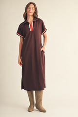 woman wearing a brown midi dress with a collar and striped details, paired with tan cowboy boots and standing with hands in pockets