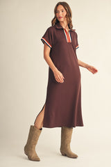 woman wearing a brown polo style dress with striped accents on the sleeves and side slits, paired with tan cowboy boots