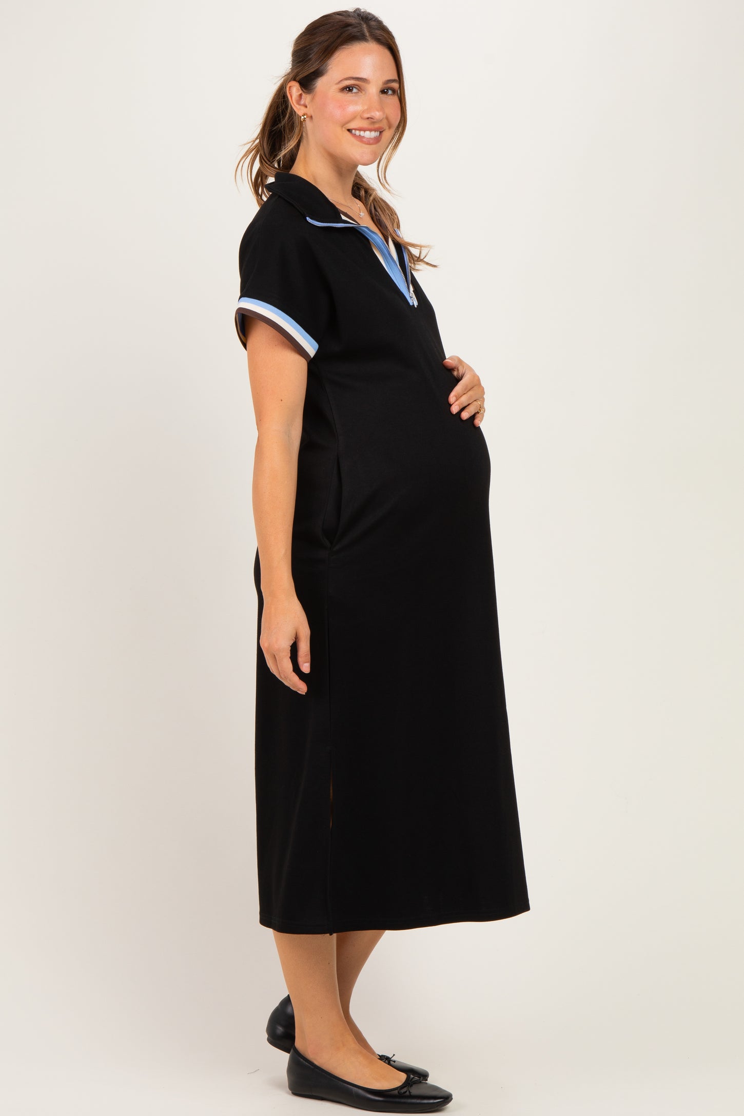 woman wearing a black maternity dress with blue collar accents and a visible baby bump