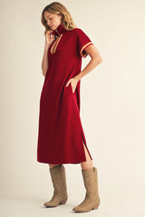 woman wearing a red polo-style dress with side slits and contrasting stripes, paired with beige cowboy boots