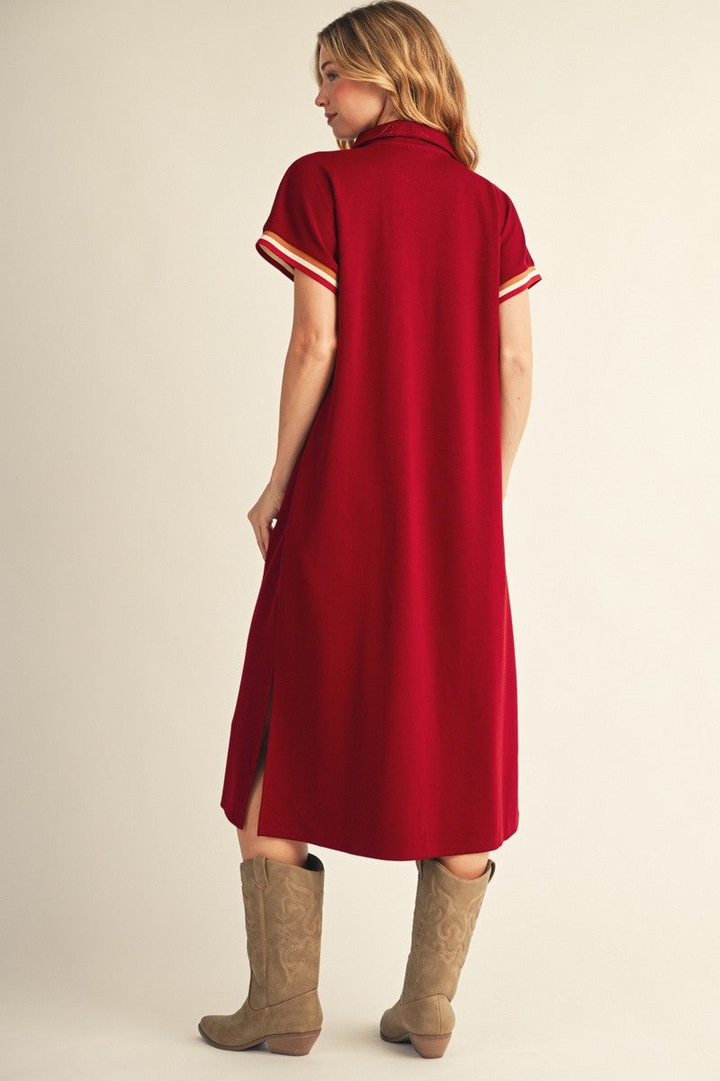 woman wearing a red short sleeve dress with striped details and a side slit, paired with brown cowboy boots