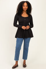 woman wearing a black long sleeve peplum top with button details and blue high-waisted jeans