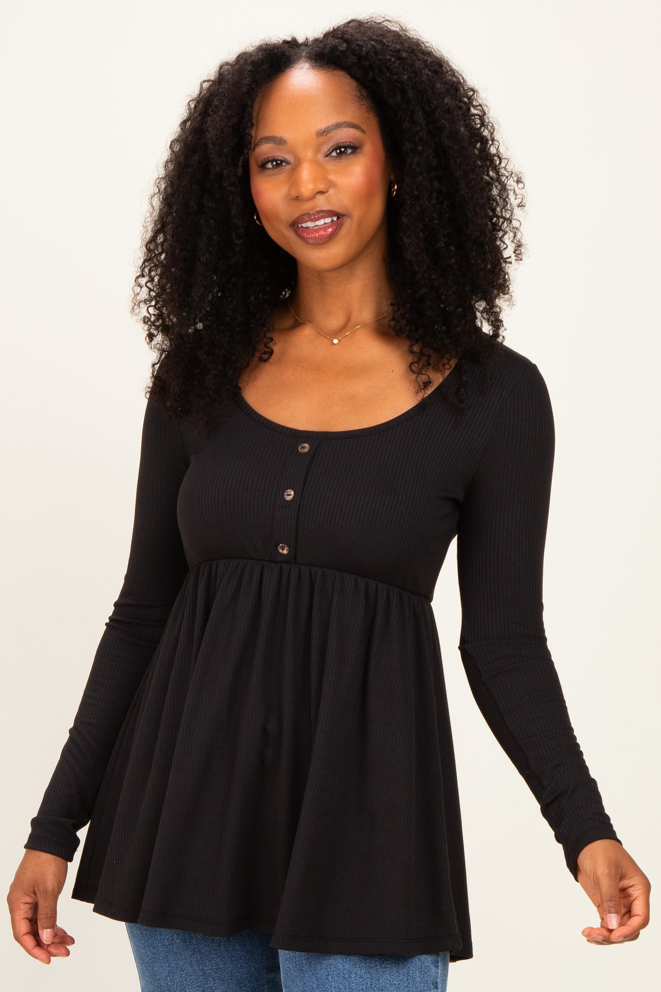 woman wearing a black long sleeve peplum top with buttons and a flared hem