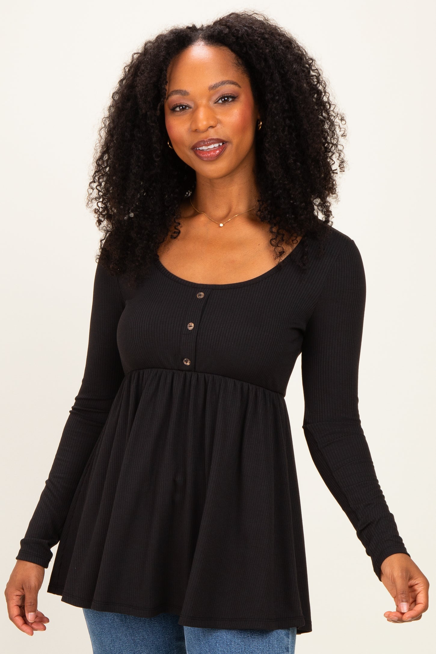 woman wearing a black long sleeve peplum top with buttons and a flared hem