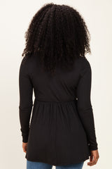woman wearing a black long sleeve tunic top with a gathered waist, view from the back