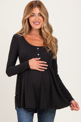 woman wearing a black long sleeve maternity top with buttons and a baby bump showing