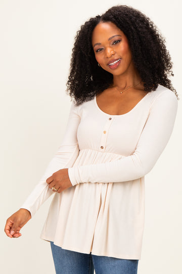 woman wearing a cream colored long sleeve button-up top with a flared hem and a scooped neckline