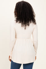 woman wearing a light pink long sleeve top with a gathered waist and back view, paired with blue jeans