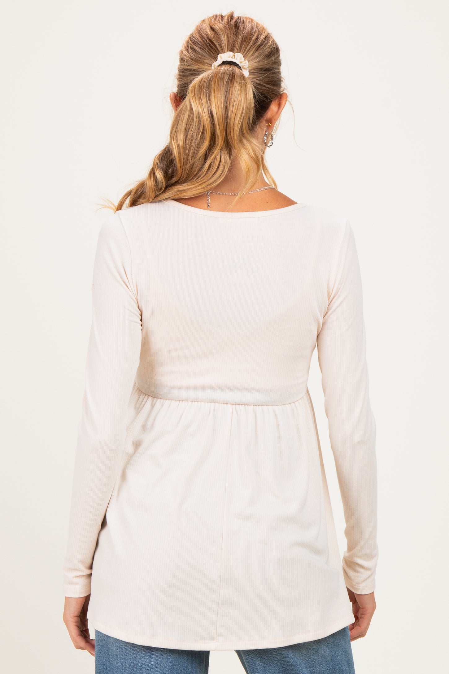 woman wearing a cream long sleeve maternity top with a fitted bust and gathered waistline, viewed from the back