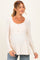 woman wearing a beige long sleeve maternity top with a button front and empire waist, showcasing her baby bump