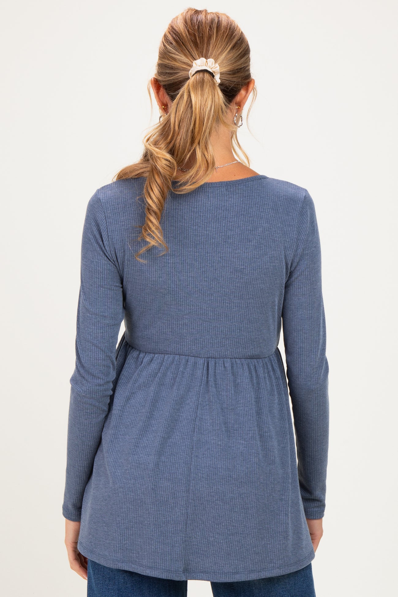 woman wearing a blue long sleeve maternity top with a flared waist and ribbed texture, showing her back