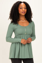 woman wearing a green ribbed peplum top with long sleeves and button details