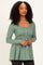 woman wearing a green ribbed peplum top with long sleeves and button details
