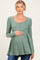 woman wearing a sage green long sleeve maternity top with a scoop neckline and button details, holding her baby bump