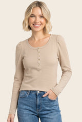 woman wearing a beige striped long sleeve henley top with button details and a round neckline, paired with blue jeans