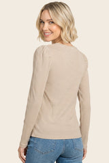 woman wearing a beige and white striped long sleeve top with puffed shoulders, smiling and facing the side