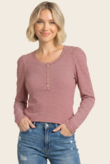 woman wearing a red and white striped long sleeve henley top with button details and smiling at the camera